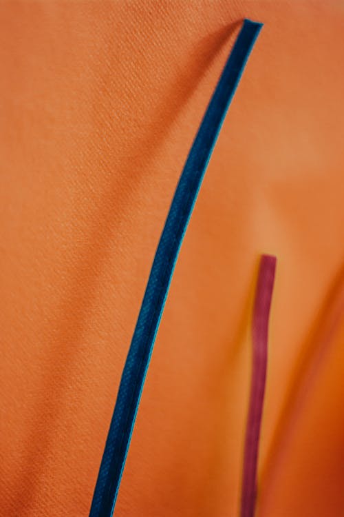 Close-up of a Blue and Pink Straws next to an Orange Wall 