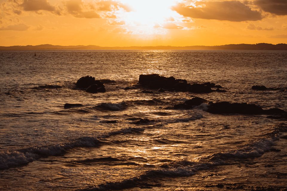 Sunset over rocks and surf — Lucas Andrade on Pexels