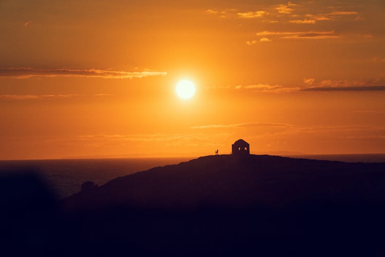 Silhouette Of A Building On A Hill At Sunset 