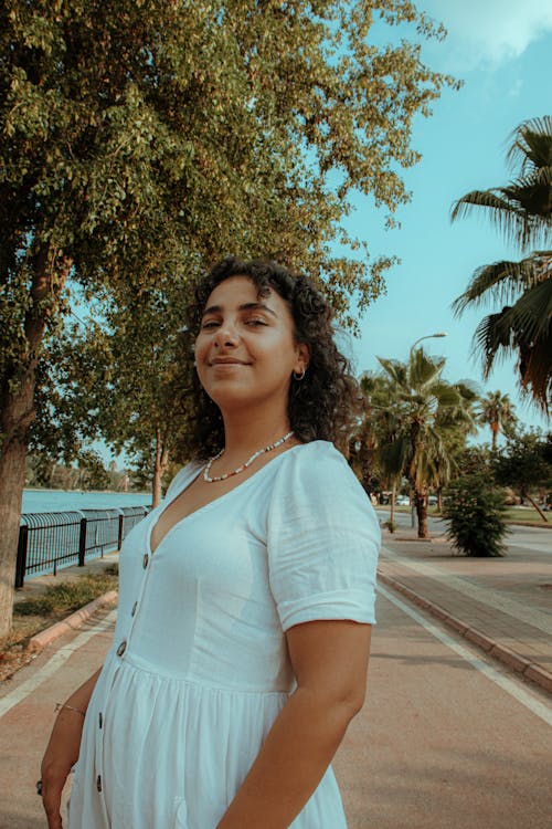 A Woman in White Dress Standing on Sidewalk