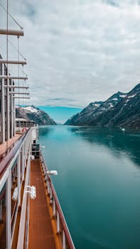 Experience stunning fjord views from a cruise ship deck, surrounded by serene turquoise water and majestic mountains.