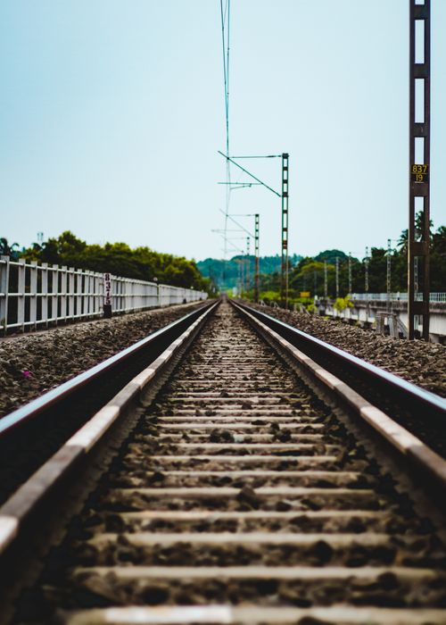 Free Dynamic low-angle view of railway tracks extending into the horizon, surrounded by lush greenery. Stock Photo