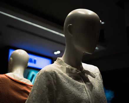 Close-up of faceless mannequins showcasing lace and gingham fashion indoors.