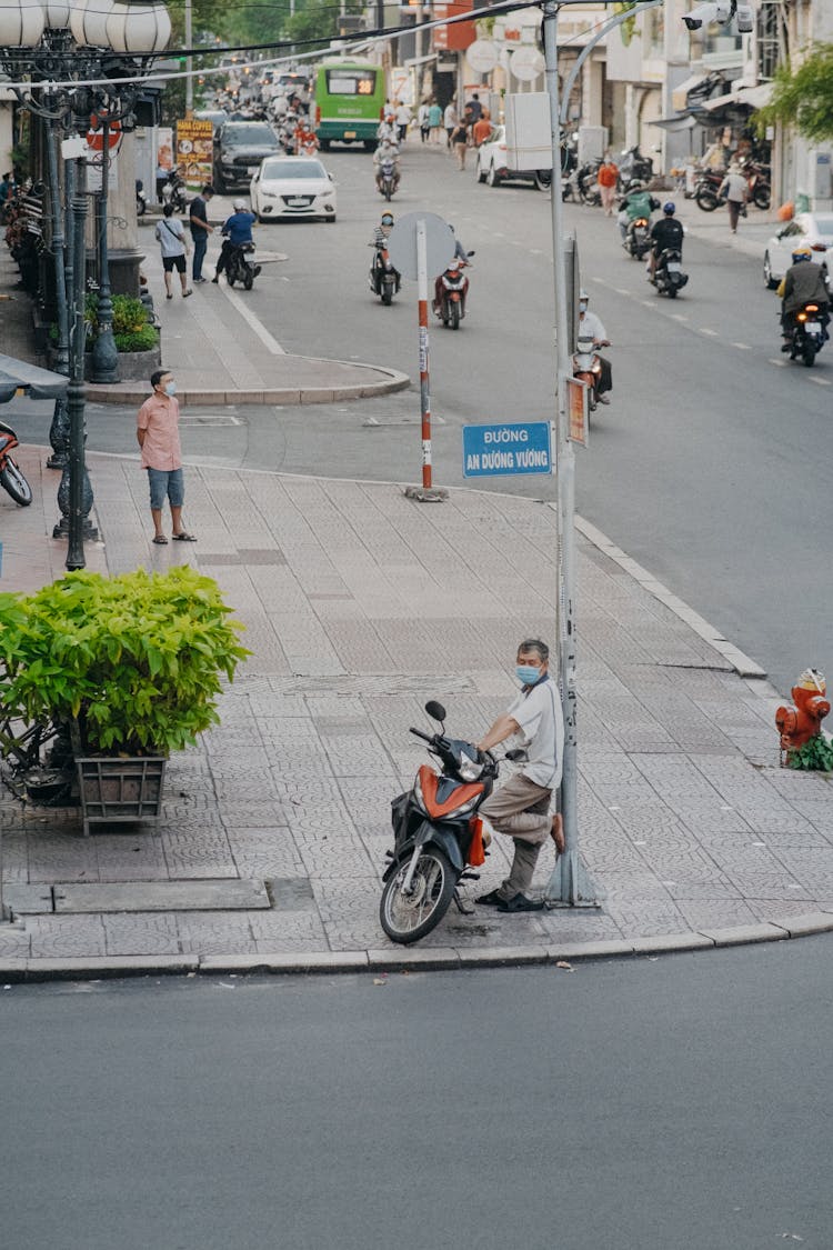 Elderly Man Leaning On A Metal Post 