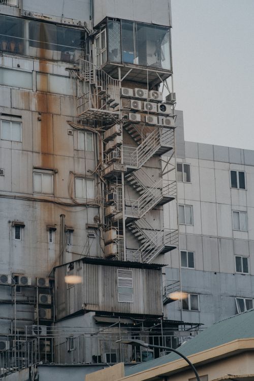 Free Weathered exterior featuring a rusty facade and fire escape staircase. Stock Photo