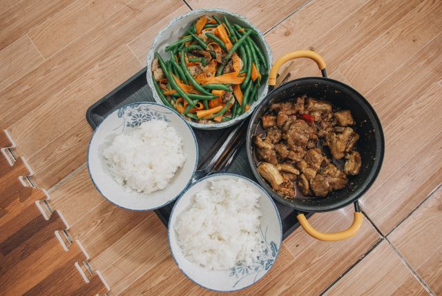 Close-up of a tasty Asian meal featuring pork, vegetables, and rice, beautifully arranged.