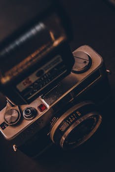 A classic vintage camera with flash in a moody setting, showcasing retro photography equipment.