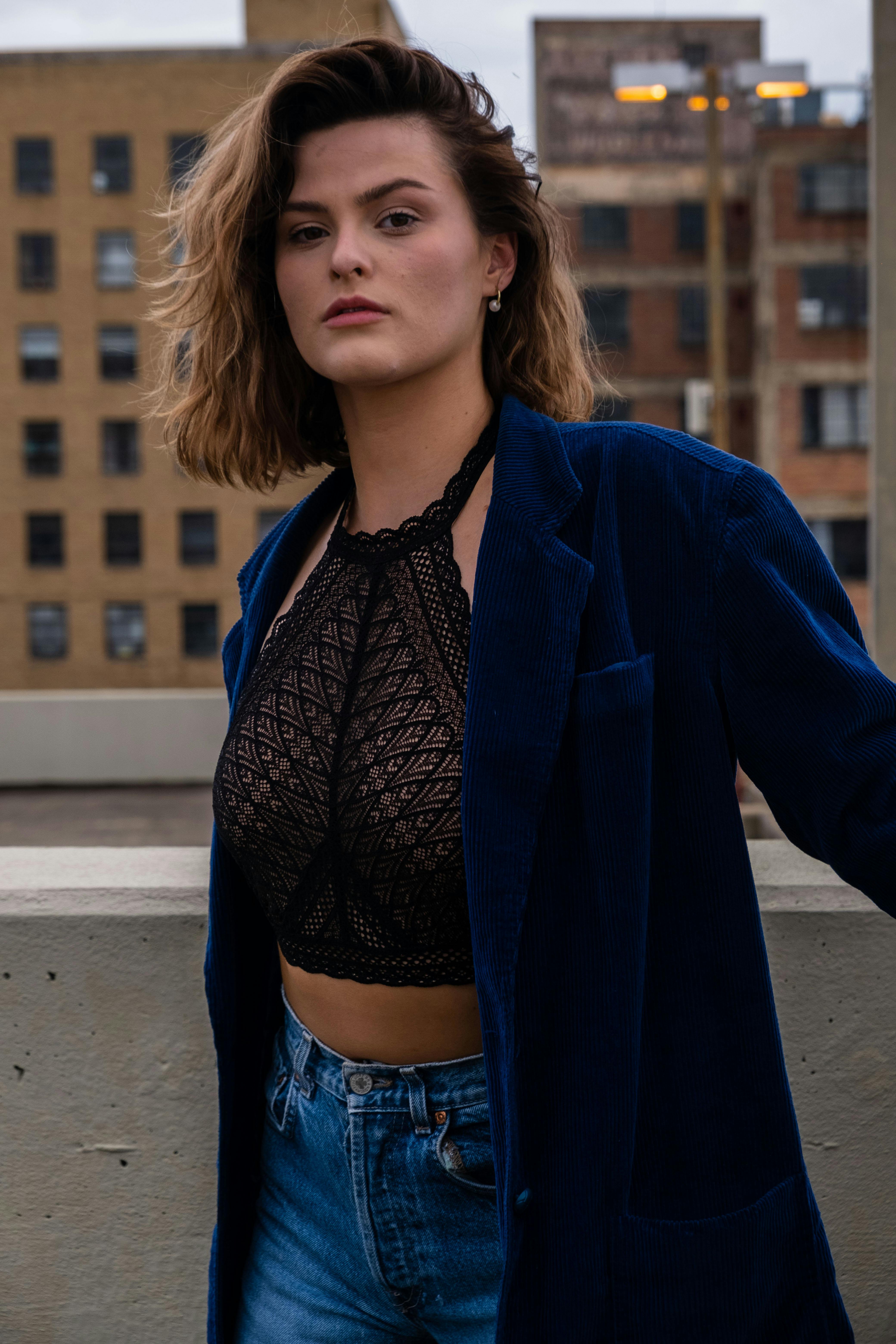 Stylish woman in a blue jacket and lace top in an urban setting, showcasing confidence.