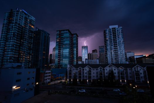 A dramatic urban skyline at night with a striking lightning bolt illuminating the cityscape.
