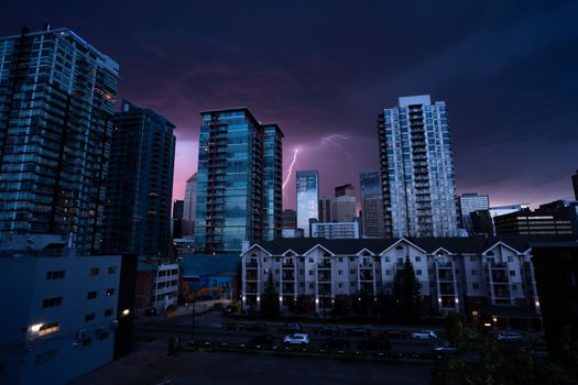 Urban skyline illuminated by a dramatic lightning strike against the night sky, showcasing towering skyscrapers.