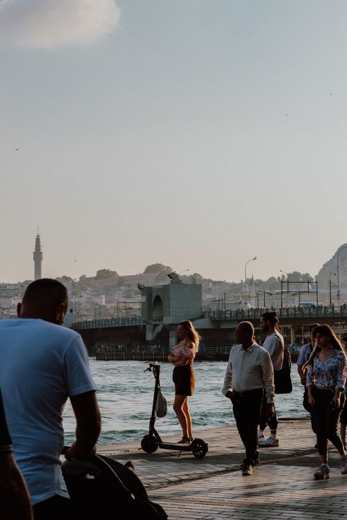Free People walking and enjoying a calm evening by the Bosphorus in Istanbul, Turkey, with a view of Galata Bridge. Stock Photo