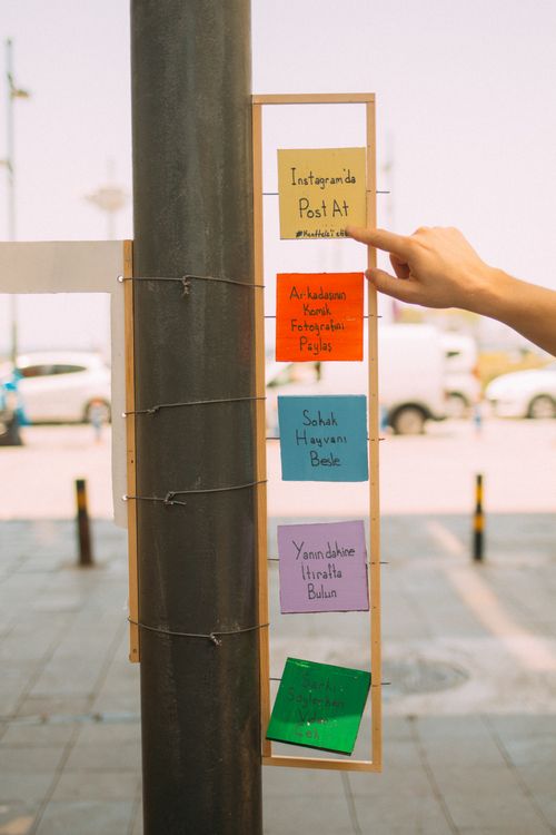Free Hand placing colorful sticky notes on a pole outdoors, creating a vibrant and interactive display. Stock Photo