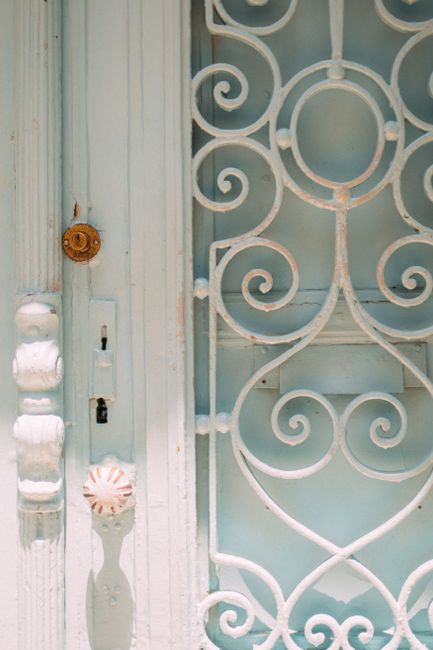 Detailed view of an ornate vintage metal door with white paint and decorative patterns.