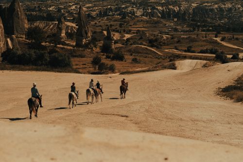 Free Tourists enjoy horseback riding across the unique landscape of Cappadocia, Turkey. Stock Photo