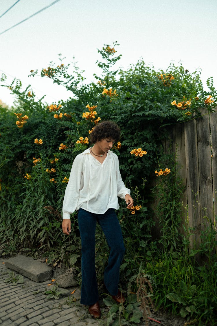 Hippie Man Posing Near Fence With Plants