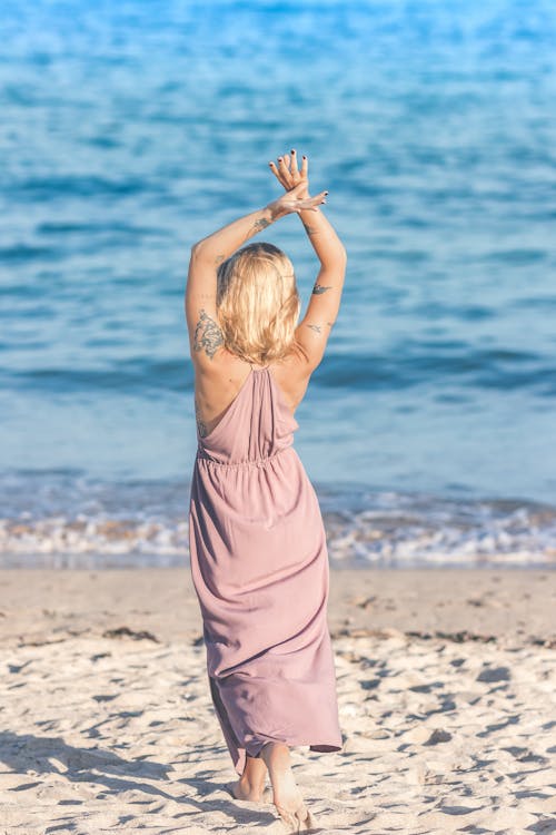 Free Woman Facing Body of Water Raising Her Hands Up Stock Photo