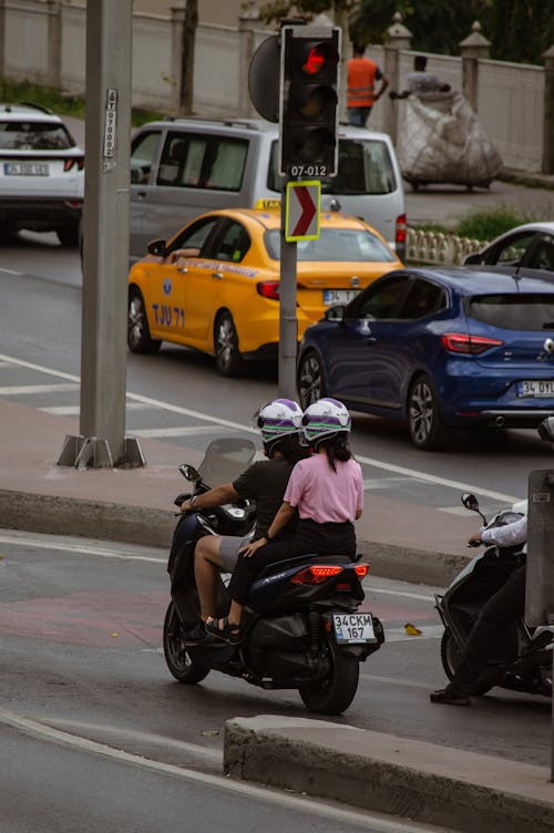 Two People riding a Scooter on a City Road 