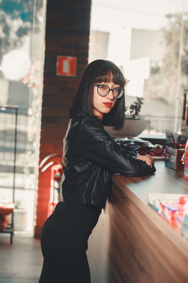 Woman In Black Leather Jacket Leaning On A Counter