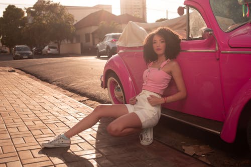 Beautiful Woman in Pink Top leaning on a Pink Car 