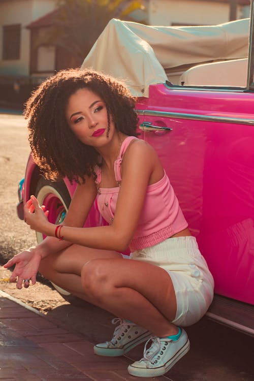Woman Crouching beside a Pink Car
