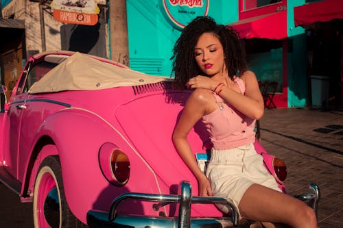 Photo of a Woman Leaning on a Pink Car