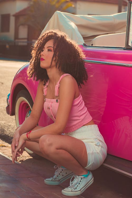 Woman Crouching near Pink Car