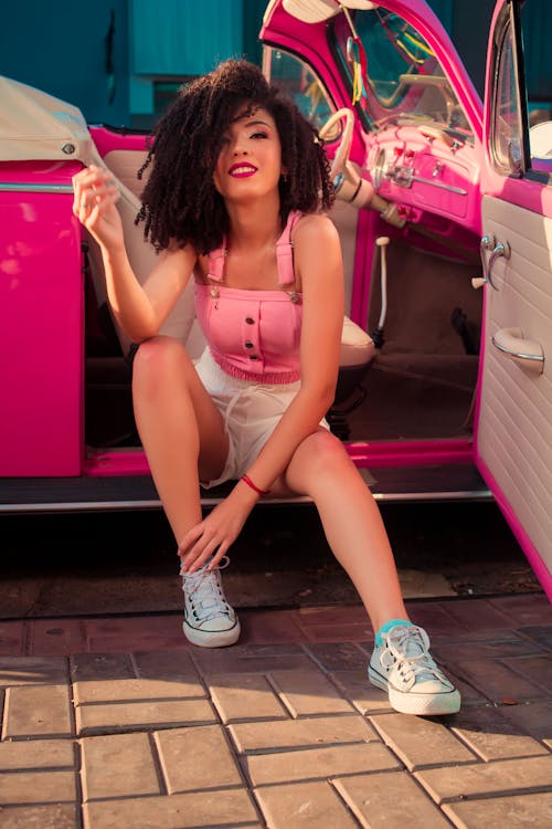 Woman in Pink Tank Top Sitting Beside a Car