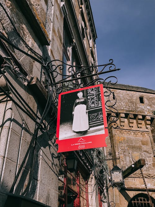 A Signage with a Picture of a Woman Hanging Beside Brown Concrete Wall