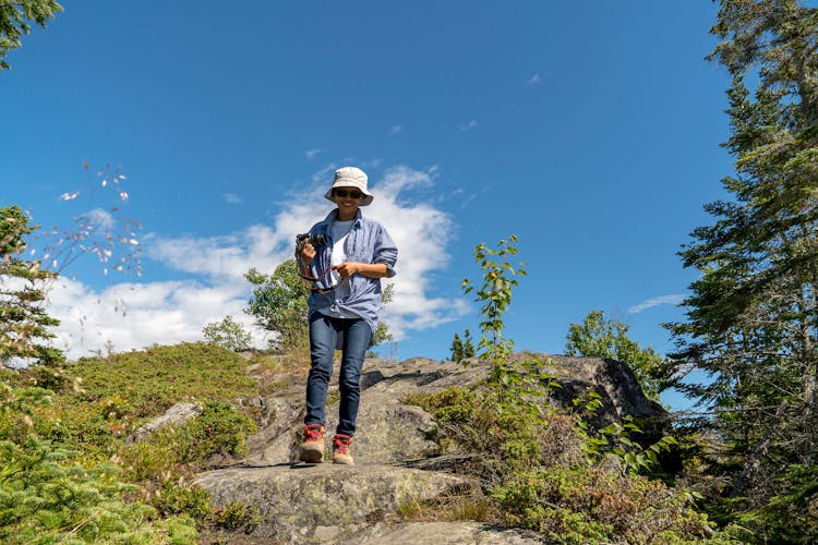 Man With Camera Walking On Rocks In Mountains