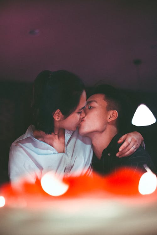 Free Man and Woman Kissing Near Pendant Lamp Stock Photo