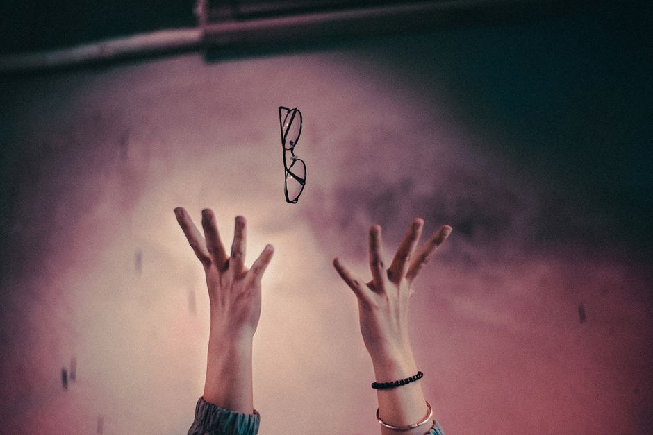 Artistic capture of hands tossing eyeglasses in Hanoi, invoking emotion and creativity.