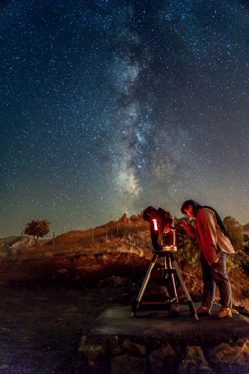 Woman with Telescope under Clear Night Sky with Stars