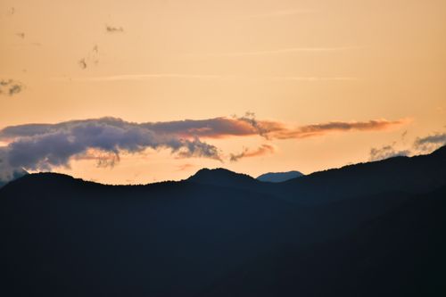 Free A tranquil view of mountain silhouettes against a golden sky at sunset. Stock Photo