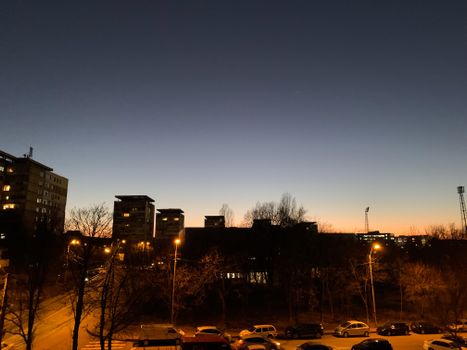 City skyline at dusk with illuminated streetlights and clear evening sky, showcasing urban tranquility.