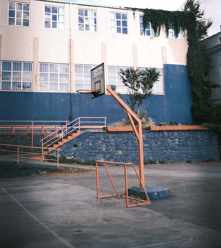 Old Basketball Hoop And A Concrete Court In A School Yard 