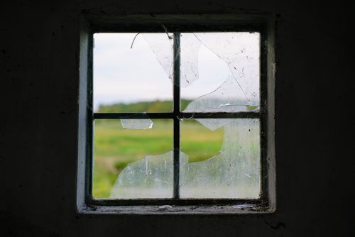 Free Close-up of a broken window with a green landscape visible through the glass. Stock Photo