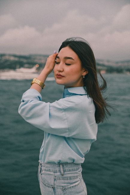 A woman standing by the ocean with eyes closed, feeling the wind.