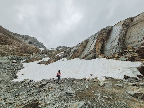 A Back View of a Person Walking on a Snow Covered Mountain