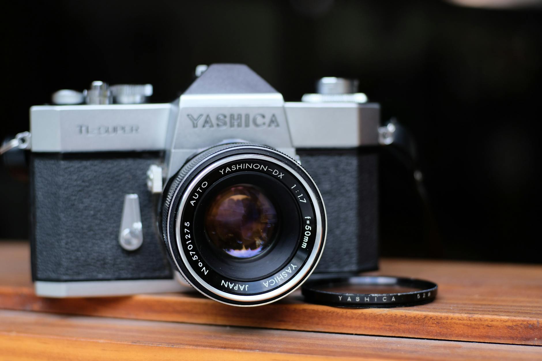 Close-up of a classic Yashica film camera with lens on wooden table.