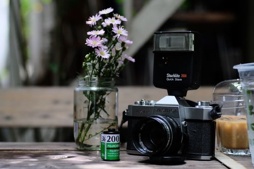 Free Classic film camera with flowers and film roll on wooden table. Stock Photo