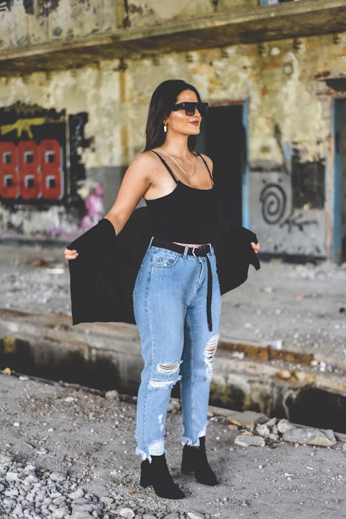 Free Woman in Black Tank Top and Blue Denim Jeans Wearing Black Sunglasses Stock Photo