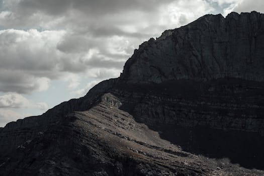 A stunning view of Mount Olympus under an overcast sky, showcasing its rugged terrain and dramatic lighting.