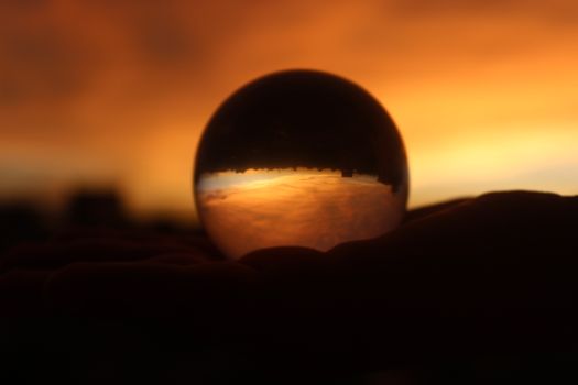 Stunning sunset reflection captured through a glass sphere, revealing a dreamy landscape.