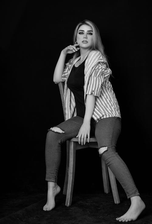 Grayscale Photo of a Woman Sitting on a Chair 