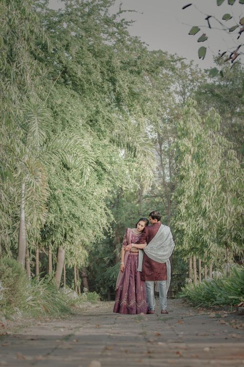 Free A loving couple embraces while strolling through a tree-lined path in a park. Stock Photo