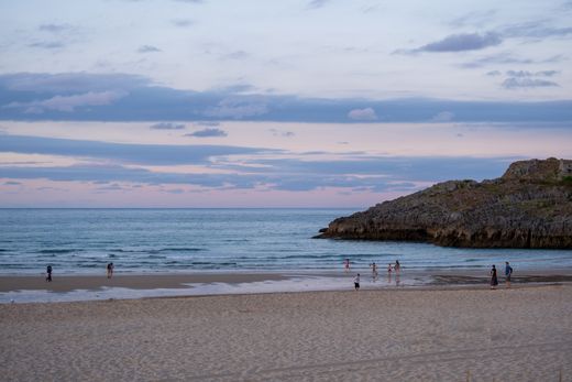 Peaceful beach at sunset with people along the shoreline, photo by Joost van Os on Pexels