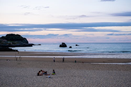 People on Shore Under White Clouds