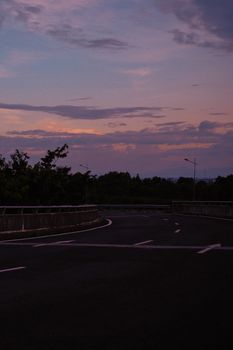A tranquil highway curve under a vibrant twilight sky, perfect for travel themes.