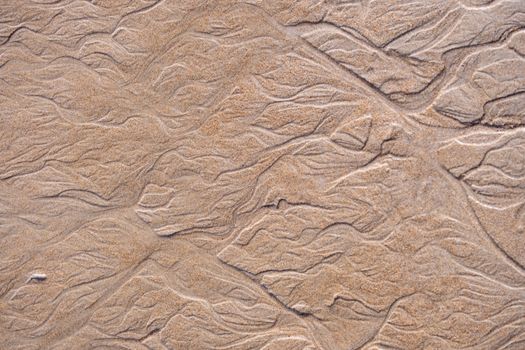 Close-up of intricate sand patterns created by natural elements, offering a textured abstract view.