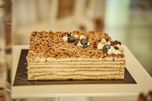A delectable layered cake topped with blueberries and nuts, perfect for dessert enthusiasts.
